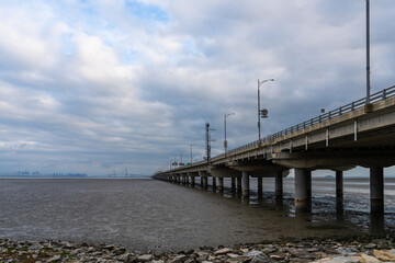 Obraz premium long bridge on mudflat beach and sea on a cloudy day