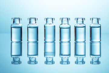 Row of Five Glass Vials with Clear Liquid on Light Blue Background.