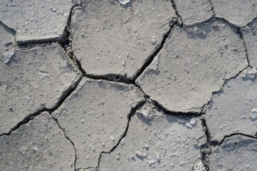 Fototapeta premium Close-up of fractured grey concrete surface with numerous plaster fragments, symbolizing division and conflict on a bright day