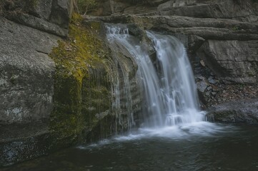 Obraz premium Water tumbling down rocky cliffs covered in algae