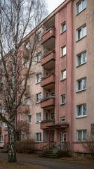 Fototapeta premium Apartment Building in a Serene Urban Environment: An aging apartment complex stands tall amidst a peaceful urban landscape. The building's facade, weathered by time.