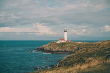 Seaside beacon with rocky shore and blue ocean under clear sky