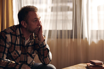 Fototapeta premium Man with depression and headache sitting on a chair at home.