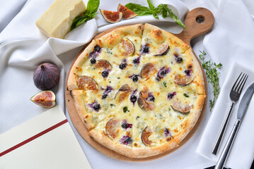 pizza with cheese, figs and berries on a white board on the table