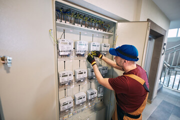 Electrician working on a modern electricity power meter station in a building. © astrosystem