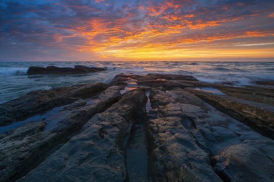 Ocean waves crashing over wet stones at dusk
