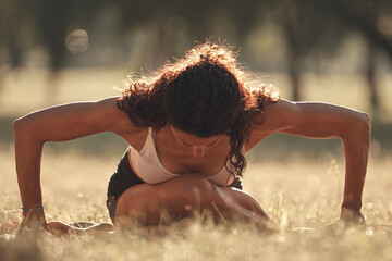 Woman practicing yoga and stretching in the park on a hot sunny summertime day.