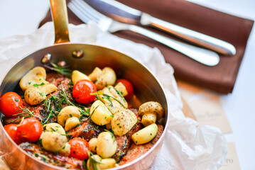 baked potatoes with vegetables and mushrooms in a copper stewpan on the table macro photo