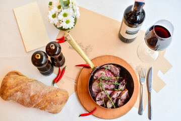 fried meat slices in cherry sauce in a copper stew pot on the table

