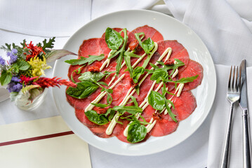 veal carpaccio on a plate of greens