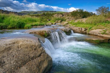 Stream cascading over stones with lush greenery behind