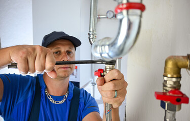Plumber hand tightening a plumbing pipe connection with a wrench