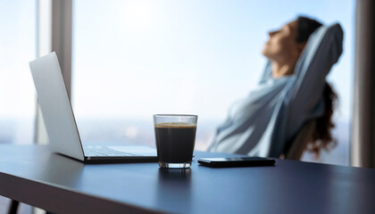 Close-up of laptop coffee mug and A smartphone is placed on a dark desk with Relaxed and blurry person .