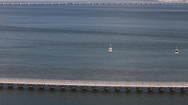 Aerial drone view of cable cars in Parque das Nacoes, Lisbon, Portugal with Vasco da Gama Bridge in the background