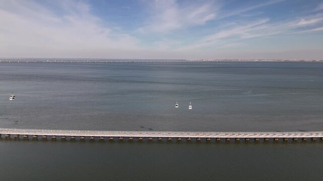 Aerial drone view of cable cars in Parque das Nacoes, Lisbon, Portugal with Vasco da Gama Bridge in the background