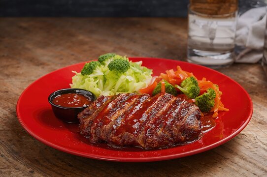Dined at a wellness eatery savoring grilled meat on a vibrant dish accompanied by wholesome veggies and tangy BBQ sauce