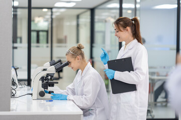 Fototapeta premium Scientists conduct research in laboratory, analyzing samples with microscope during their study