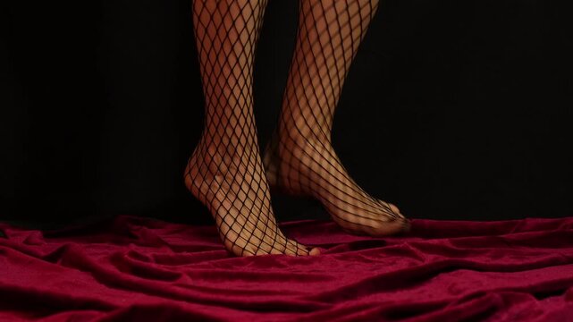 women's fragile legs in fishnet tights on a black and red background