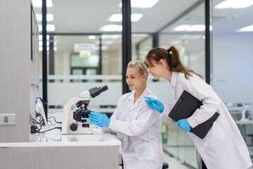 Scientists work in a modern laboratory analyzing samples under a microscope during a collaborative research session
