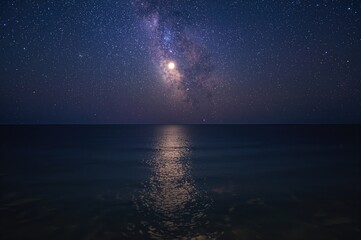 The full moon lights up the ocean's surface, reflecting the Milky Way across the sea, with countless bright stars scattered throughout the night sky.