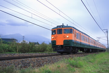 Obraz premium 浅間山に見守られて曇天の軽井沢を走行するしなの鉄道115系電車(湘南色)_2025/10/4撮影