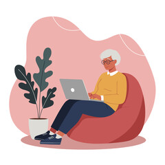 Relaxed senior woman using laptop on bean bag connecting online from home