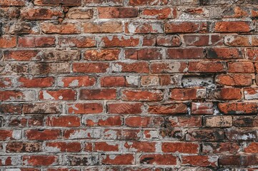 Aged dilapidated brick wall featuring white mortar patches and sections of gray bricks