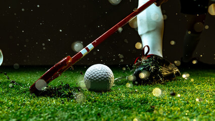 Field hockey player striking white ball on wet grass under stadium lights. Concept of motivation...