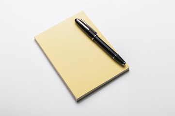 Fountain pen resting on a yellow notebook with white backdrop