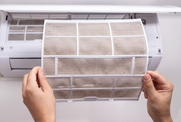Close up of dusty, clogged air filter taken out of home air conditioner. Concept of dirty indoor air, air purification, cleaning service and dust pollution.