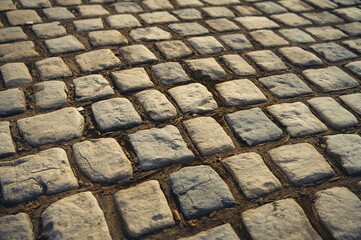Detailed shot of an aged cobblestone path featuring irregular, worn stones.