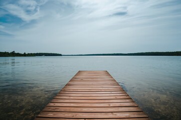 Obraz premium Wooden Deck Stretching Over Crystal Clear Water Beneath an Overcast Sky