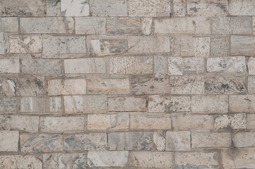 Fototapeta premium Exterior wall composed of carved marble stones varying in dimensions and hues.