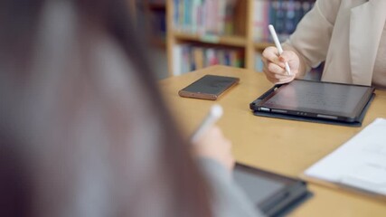 Asian woman actively using tablet and stylus during an educational or corporate training session in modern learning space. - Powered by Adobe