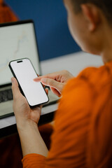 Monks and priests, men in orange robes, use smartphones with white screens.