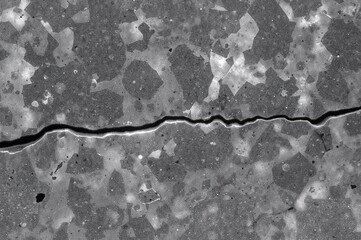 Microscopic view of fractured gray cast iron featuring a prominent continuous dark line at the center, displaying pearlitic microstructure with graphite flakes embedded in pearlite and alpha ferrite