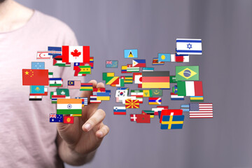 Person's hand interacting with various national flags, symbolizing international relations, globalism, and the interconnected world. Illustrates