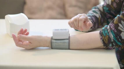 A senior woman performs her morning self-care by checking blood pressure with a digital wrist monitor, promoting independence, wellness, and preventive daily health habits.