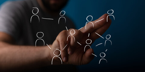 A human hand interacts with a digital network of interconnected people icons. Represents social networking, global communication, teamwork, and