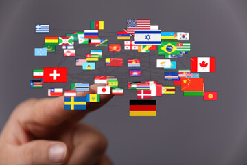 A hand touching a network of global country flags, representing international relations,...