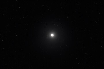 Fototapeta premium Long-range shot capturing a bright full moon against a dark, clear sky at night.