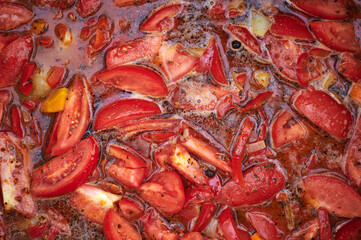 Boiling pot with tomatoes and spices during Polish harvest festival in Wloclawek, close-up view, natural light, rustic food preparation.