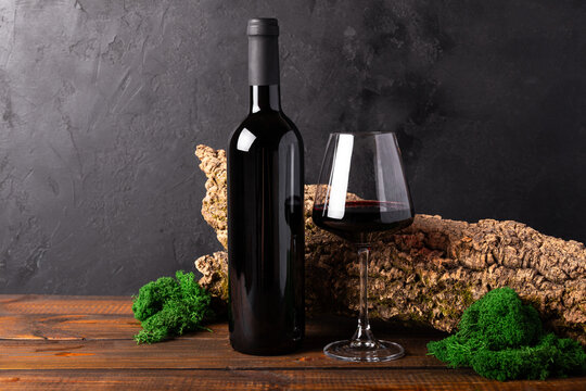 Bottle and a glass of red wine with a composition of old wood. Minimalistic composition with black background for product branding, identity, and packaging copy space for text
