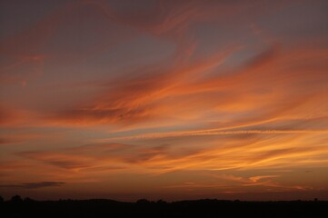 Golden hour sky adorned with vibrant orange and yellow clouds over a summery horizon