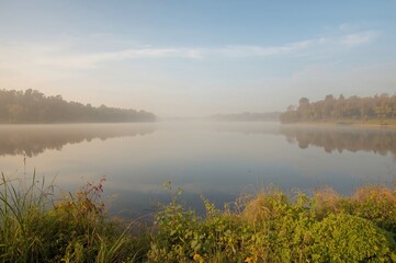 Peaceful scenery featuring a calm lake enveloped in morning fog