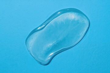 Fototapeta premium Transparent cosmetic serum gel displayed on a blue surface.