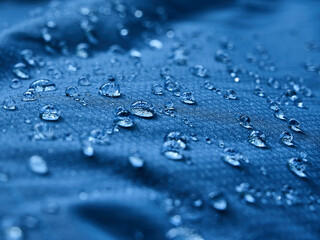 Water drops on waterproof membrane fabric. Detail view of texture of blue waterproof cloth.