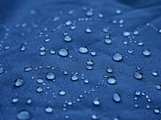 Water drops on waterproof membrane fabric. Detail view of texture of blue waterproof cloth.
