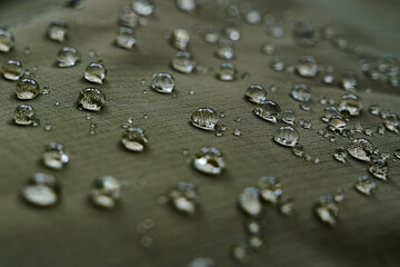 Water drops on waterproof membrane fabric. Detail view of texture of green waterproof cloth.