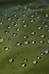 Water drops on waterproof membrane fabric. Detail view of texture of green waterproof cloth.
